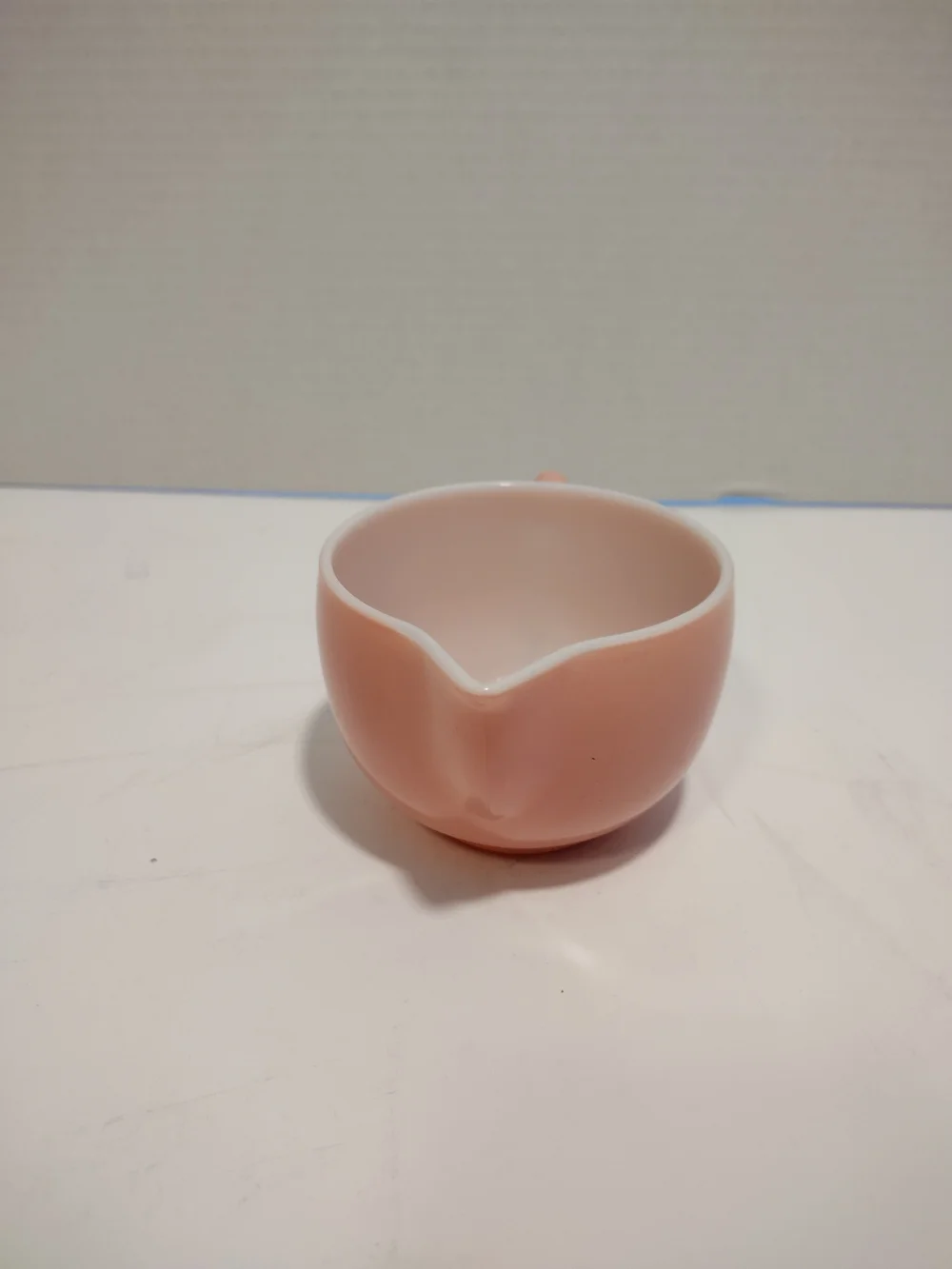 Vintage pink glass creamer by Hazel-Atlas with a C-shaped handle and spout